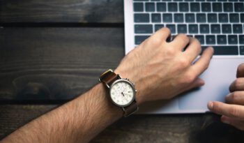 Arm mit Armbanduhr vor einer Laptoptastatur