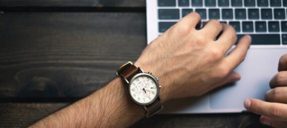 Arm mit Armbanduhr vor einer Laptoptastatur